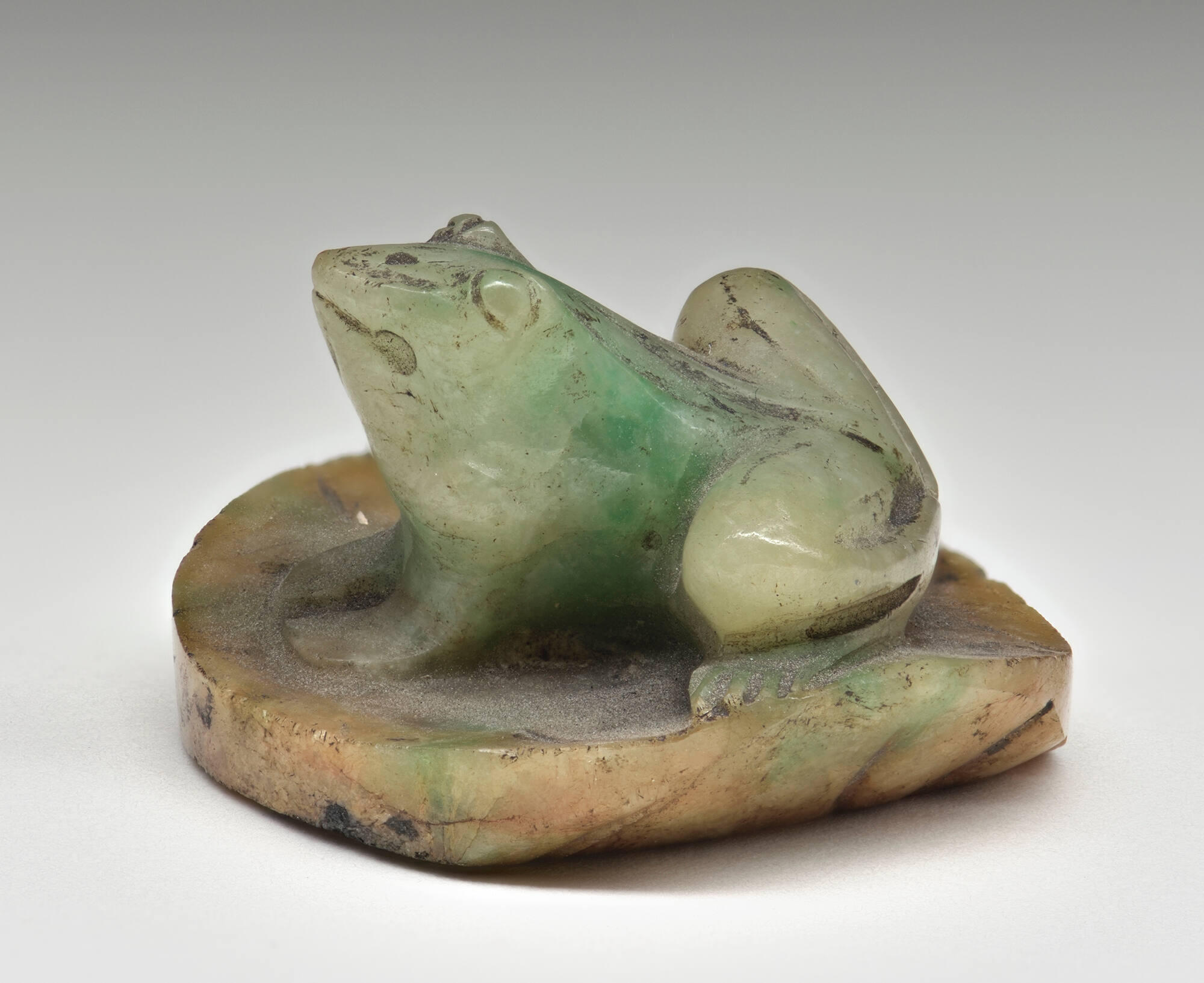 A frog carved out of light green stone.