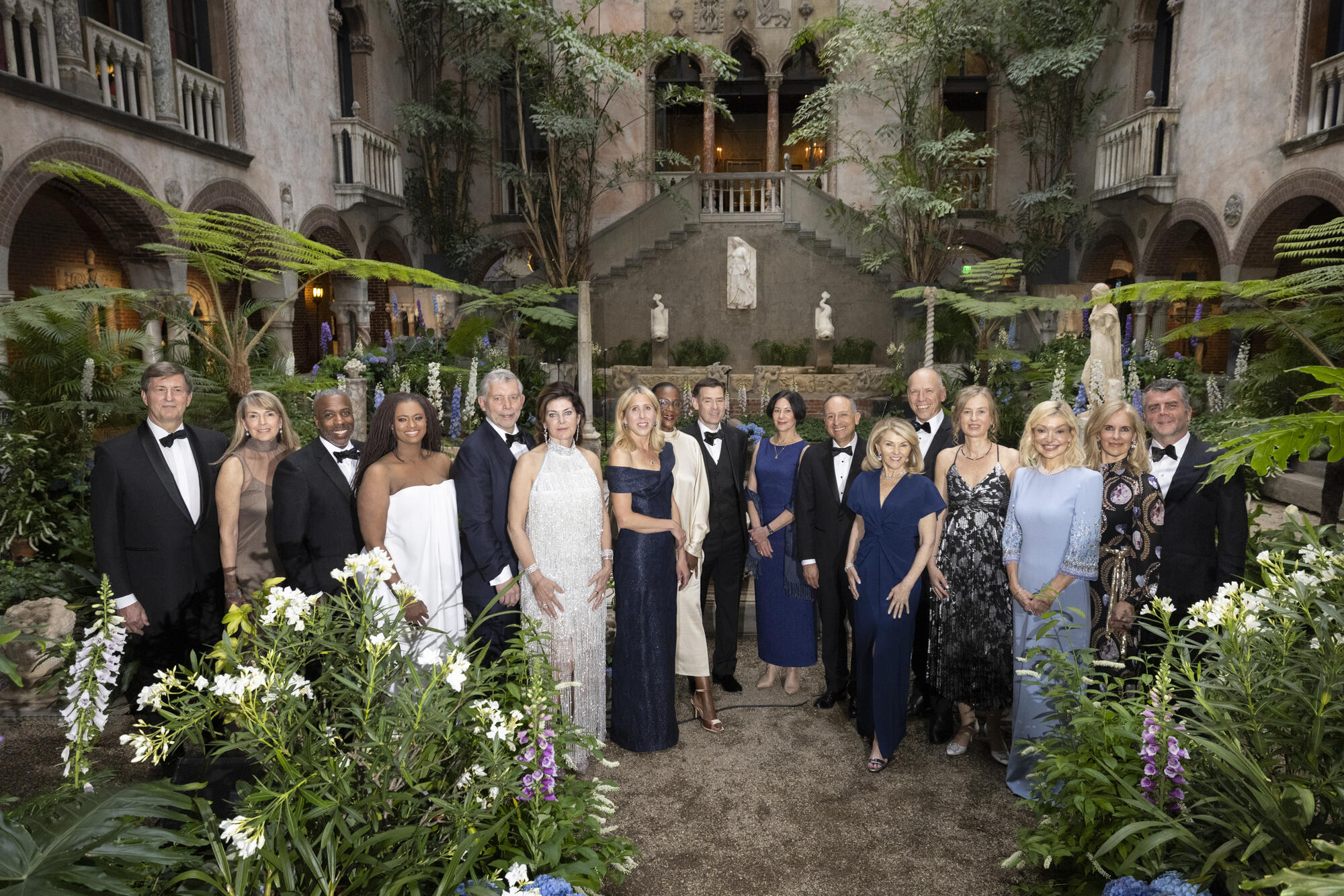 17 people in eveningwear posed in the Gardner Museum Courtyard