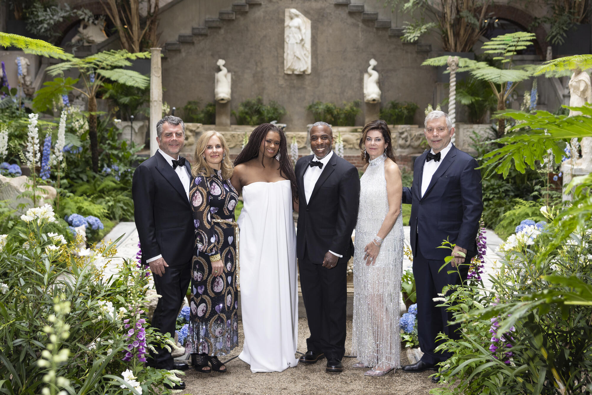6 people in eveningwear posed in the Gardner Museum Courtyard