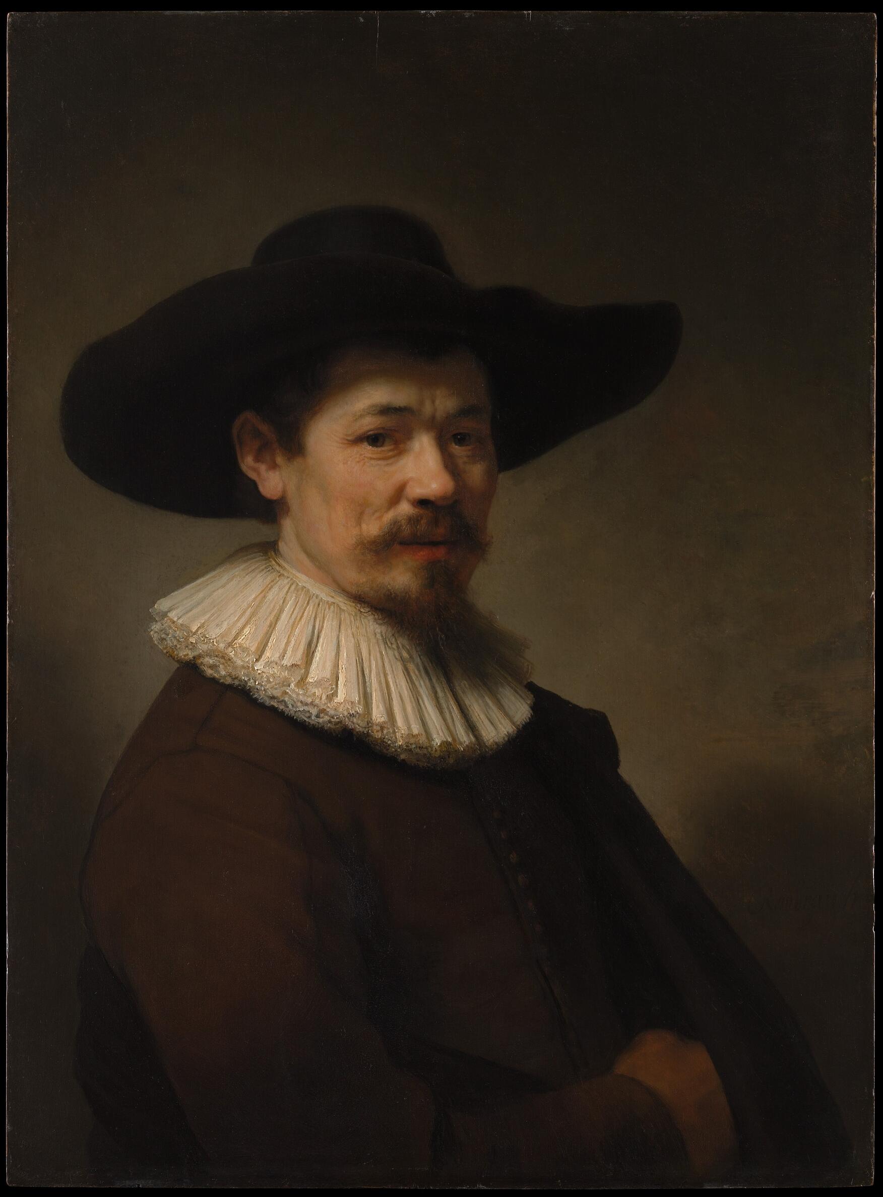 Rembrandt’s half-length portrait of a middle-aged man in black clothing and a wide-brimmed hat, seated against a dark background. Warm light highlights his face, white collar, and fur-trimmed cloak as he looks directly at the viewer.