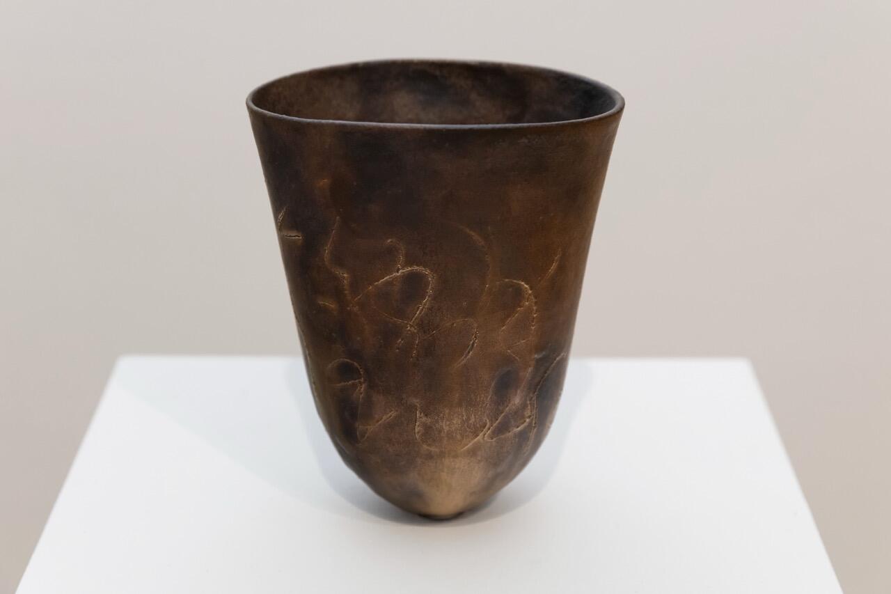 A glazed vase on a white display stand