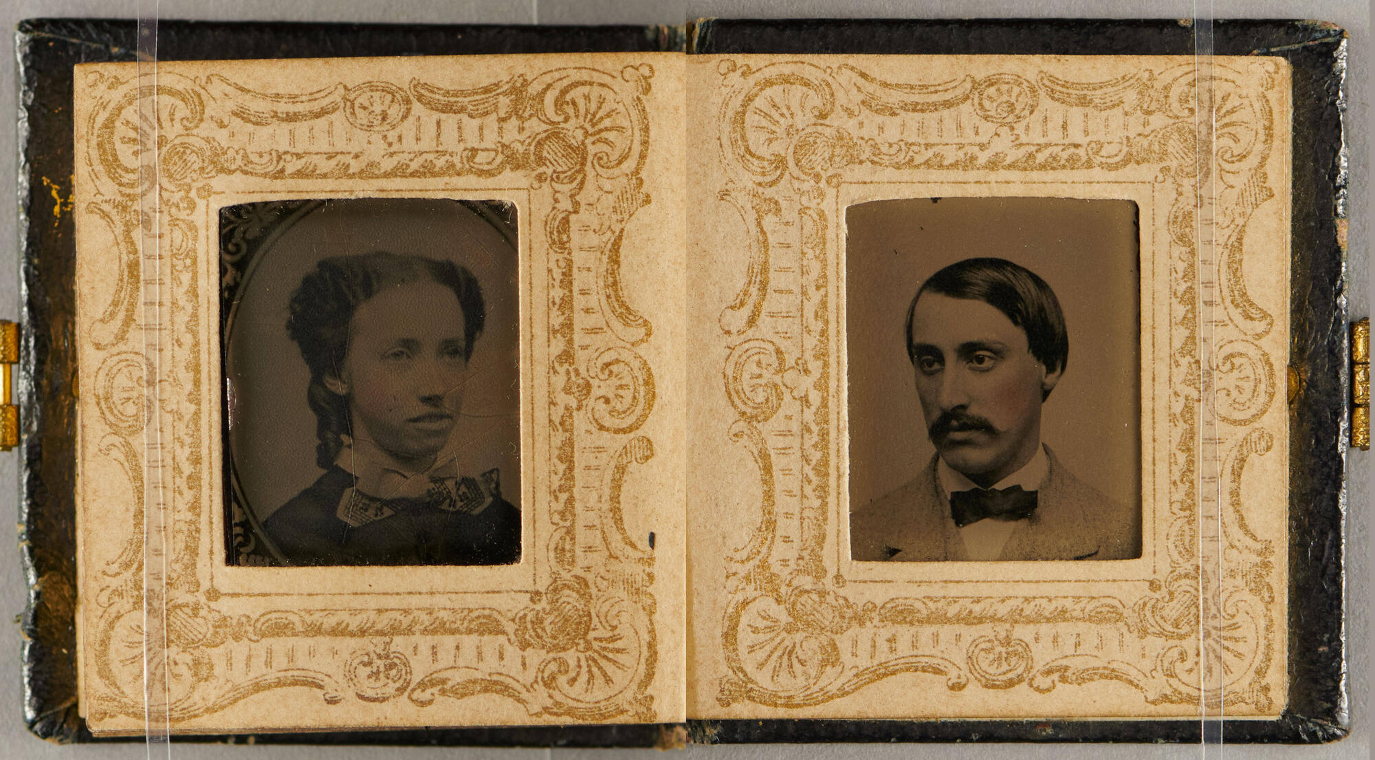 Two small photo portraits of a man and a woman, from the shoulders up, in an album with gold borders. They both have light skin, dark hair and look out diagonally to the side. The man has a mustache and a light suit with a dark bow tie, and the woman wears a dark dress.