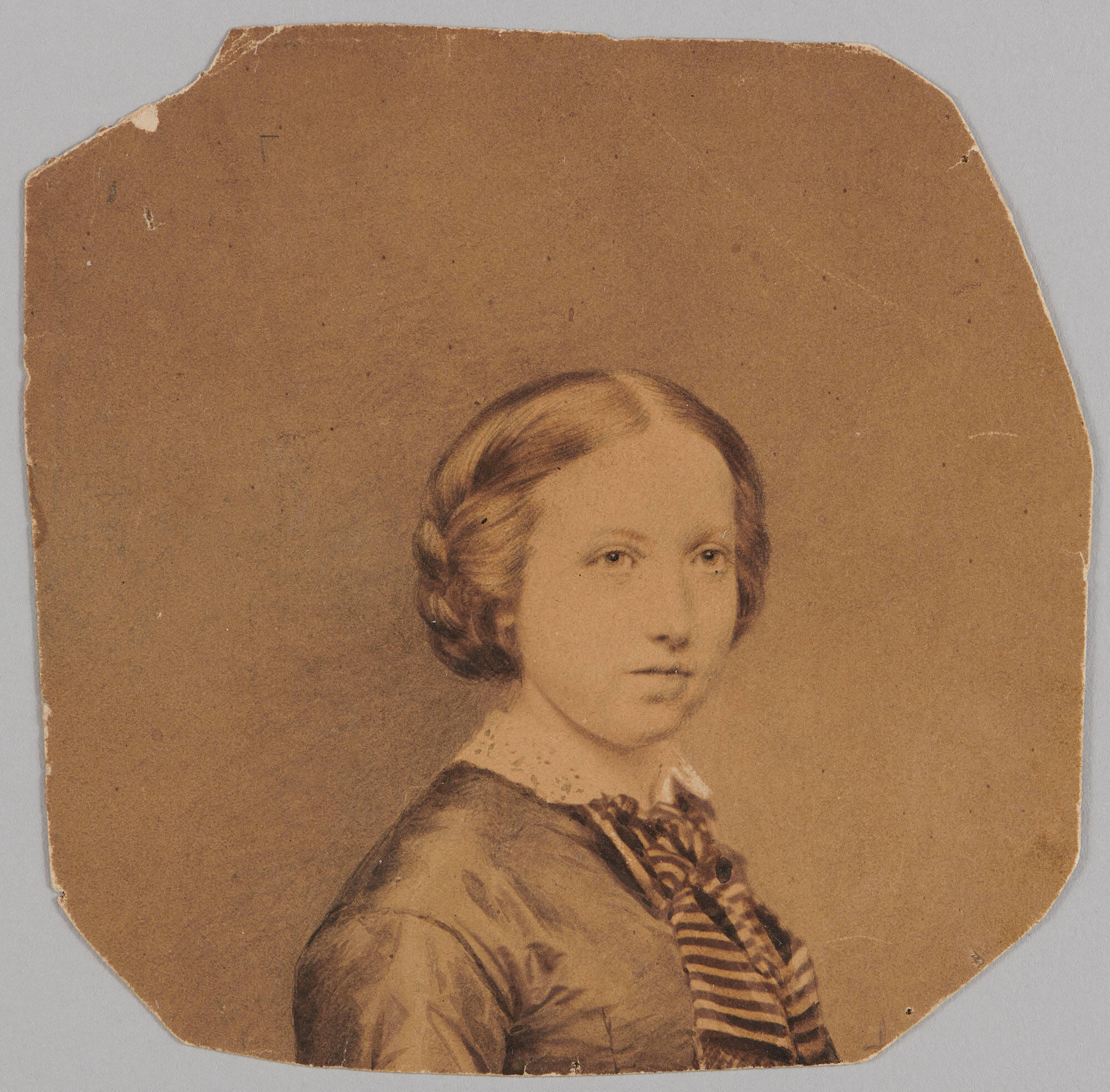 Brown-toned photograph of a girl from the bust up, with light skin and medium toned hair pulled back in a braided style. She faces diagonally to the viewer’s right and wears a dark dress with light collar and striped tie. 