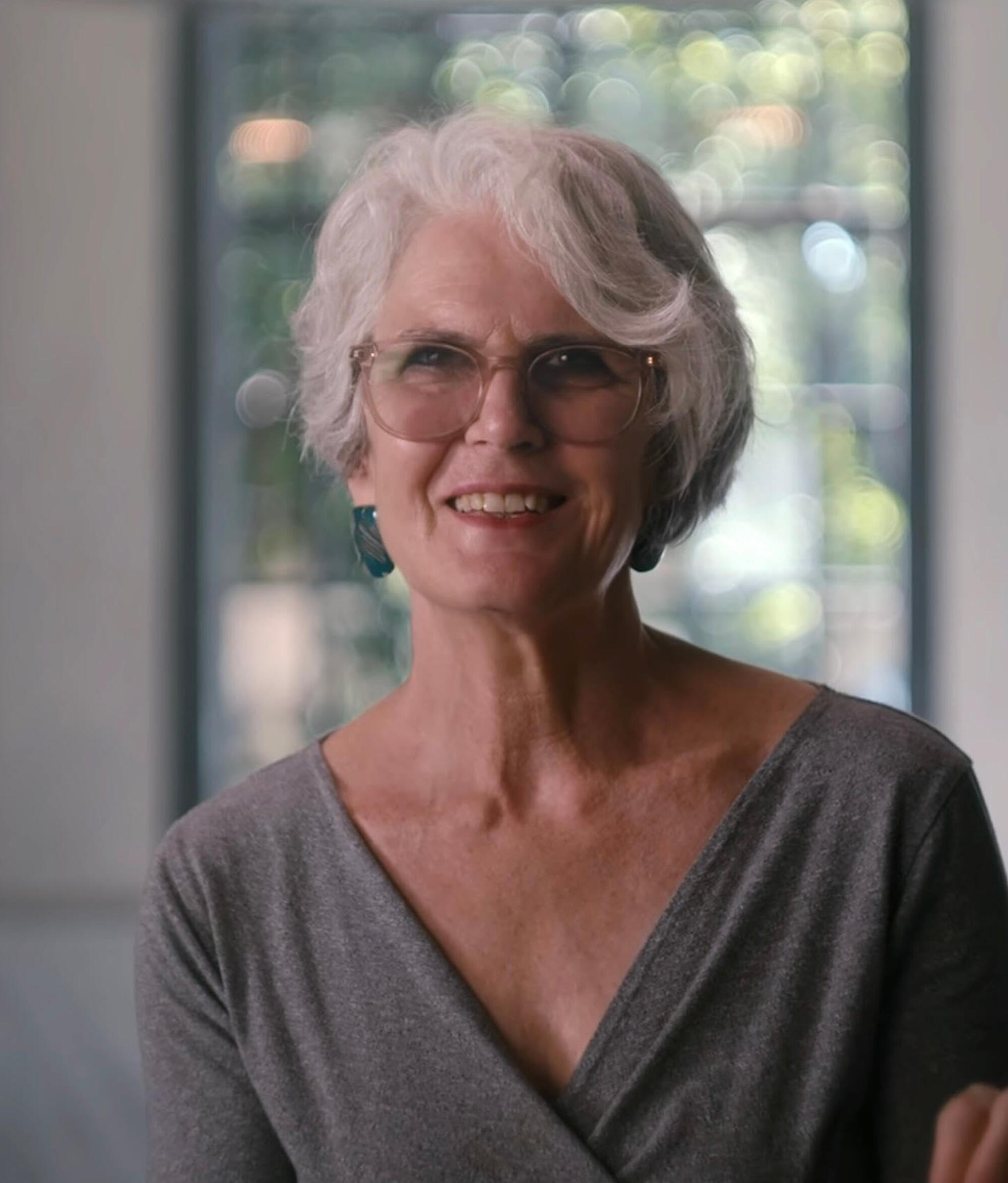 Headshot of a white woman with white hair and a grey top