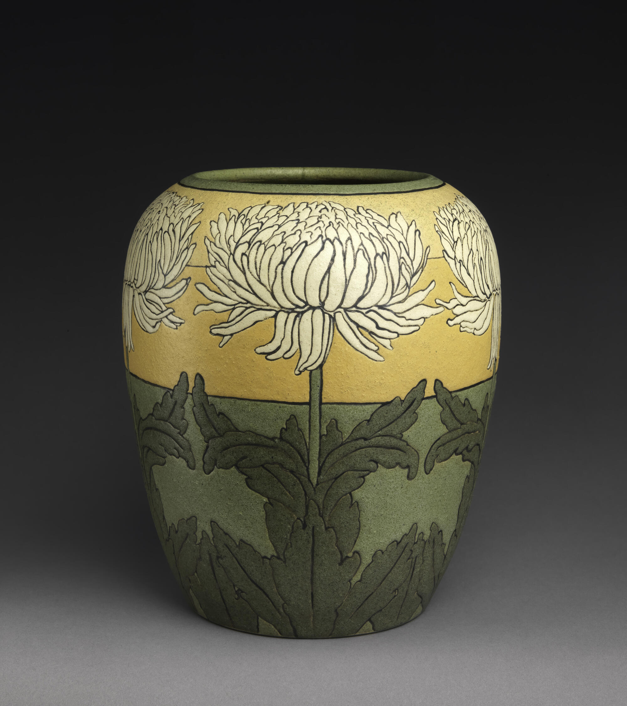 A green and yellow vase with chrysanthemum decorations.
