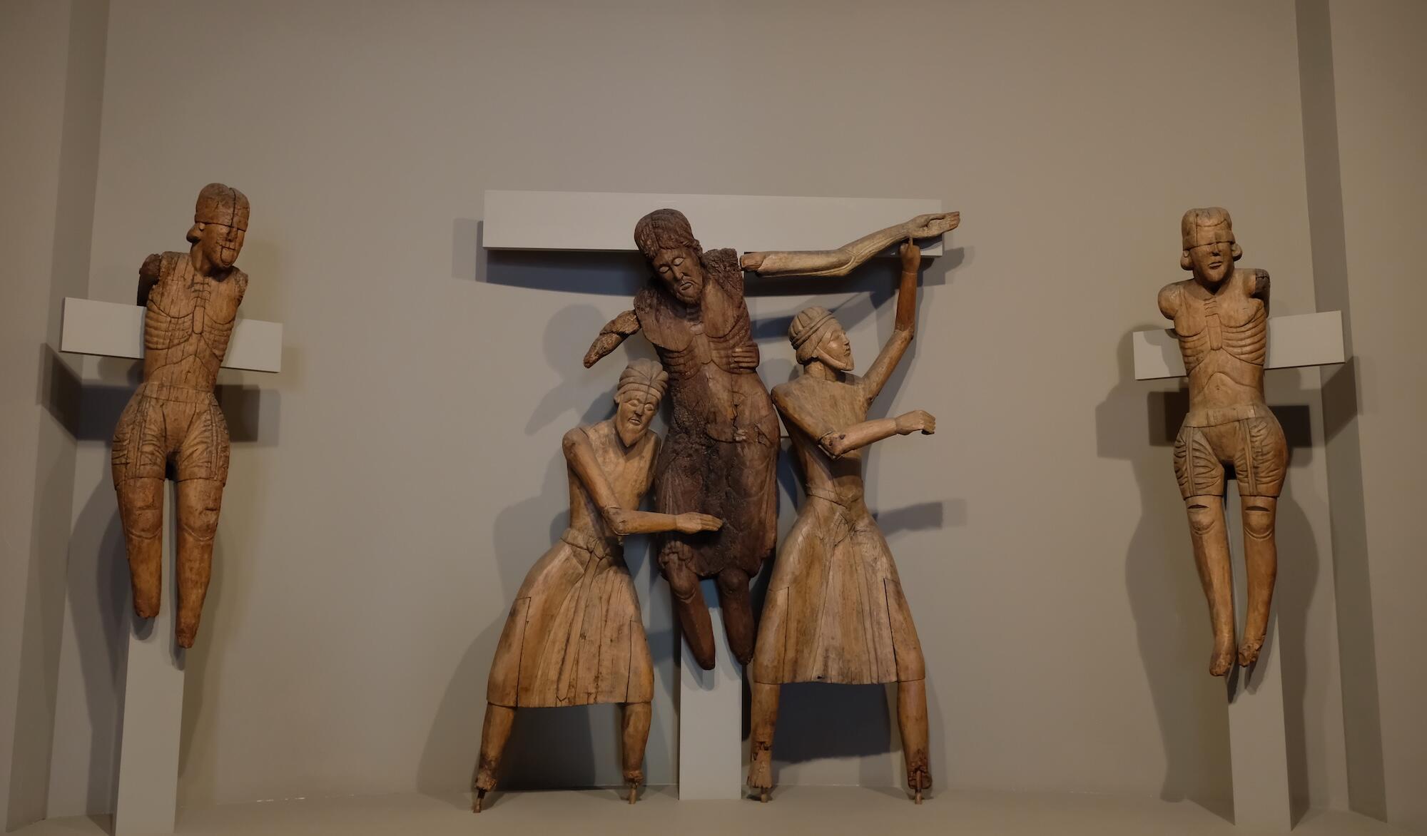 A wooden sculpture of five figures. Christ is being removed from the cross and is flanked by two other figures being crucified, the Good Thief and the Bad Thief.