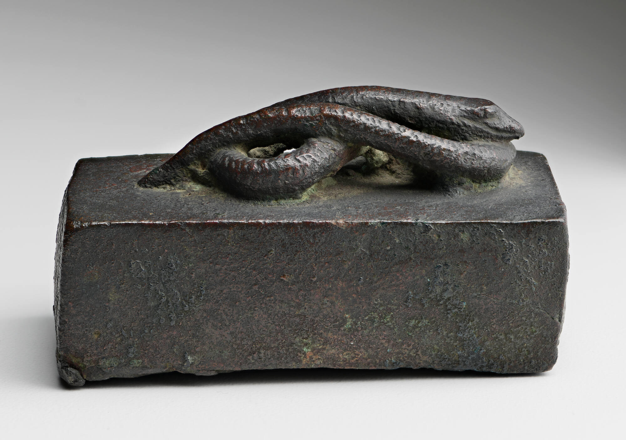 Small bronze box with the form of a coiled snake on top.