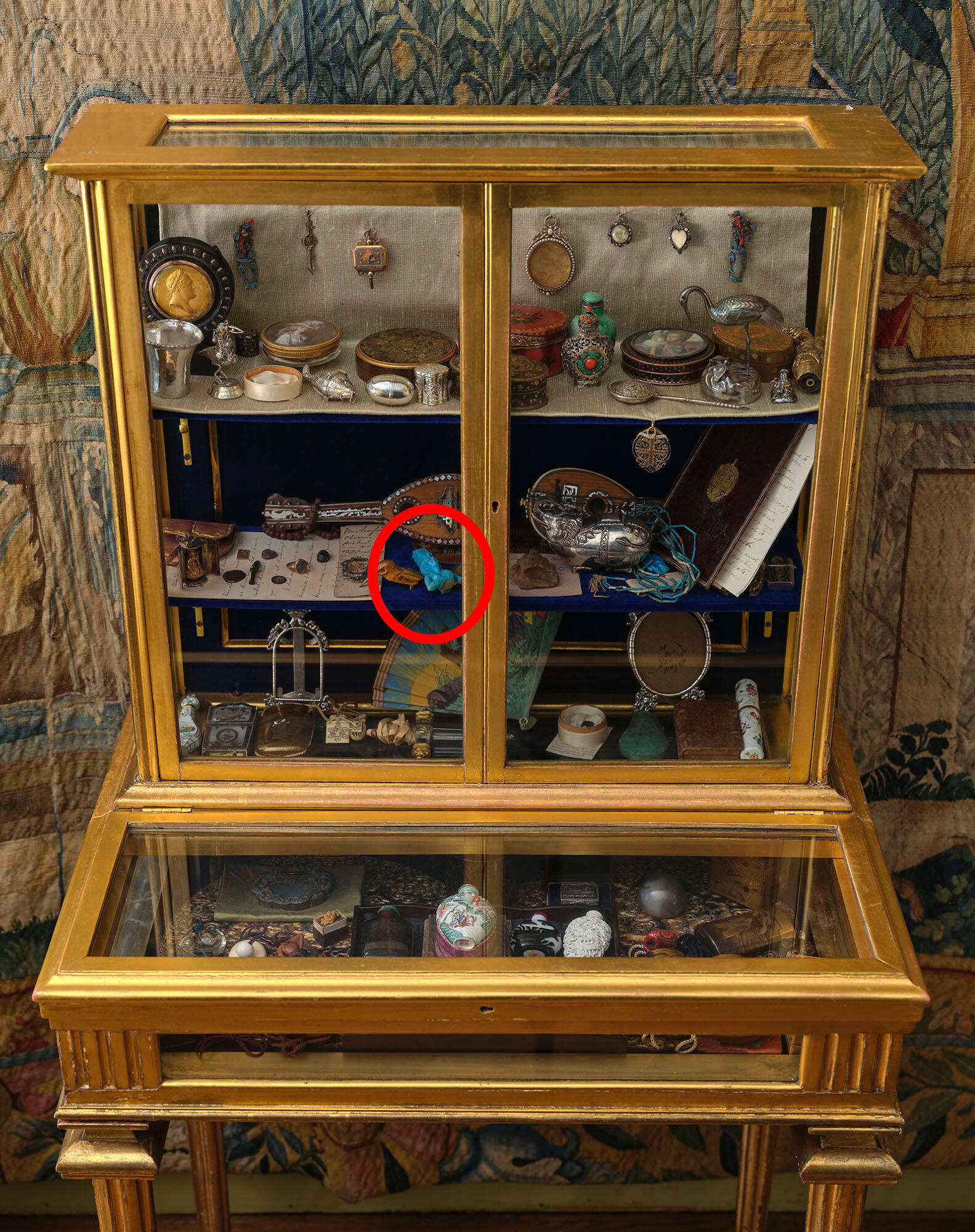 Glass and gilded wood cabinet filled with many small objects.