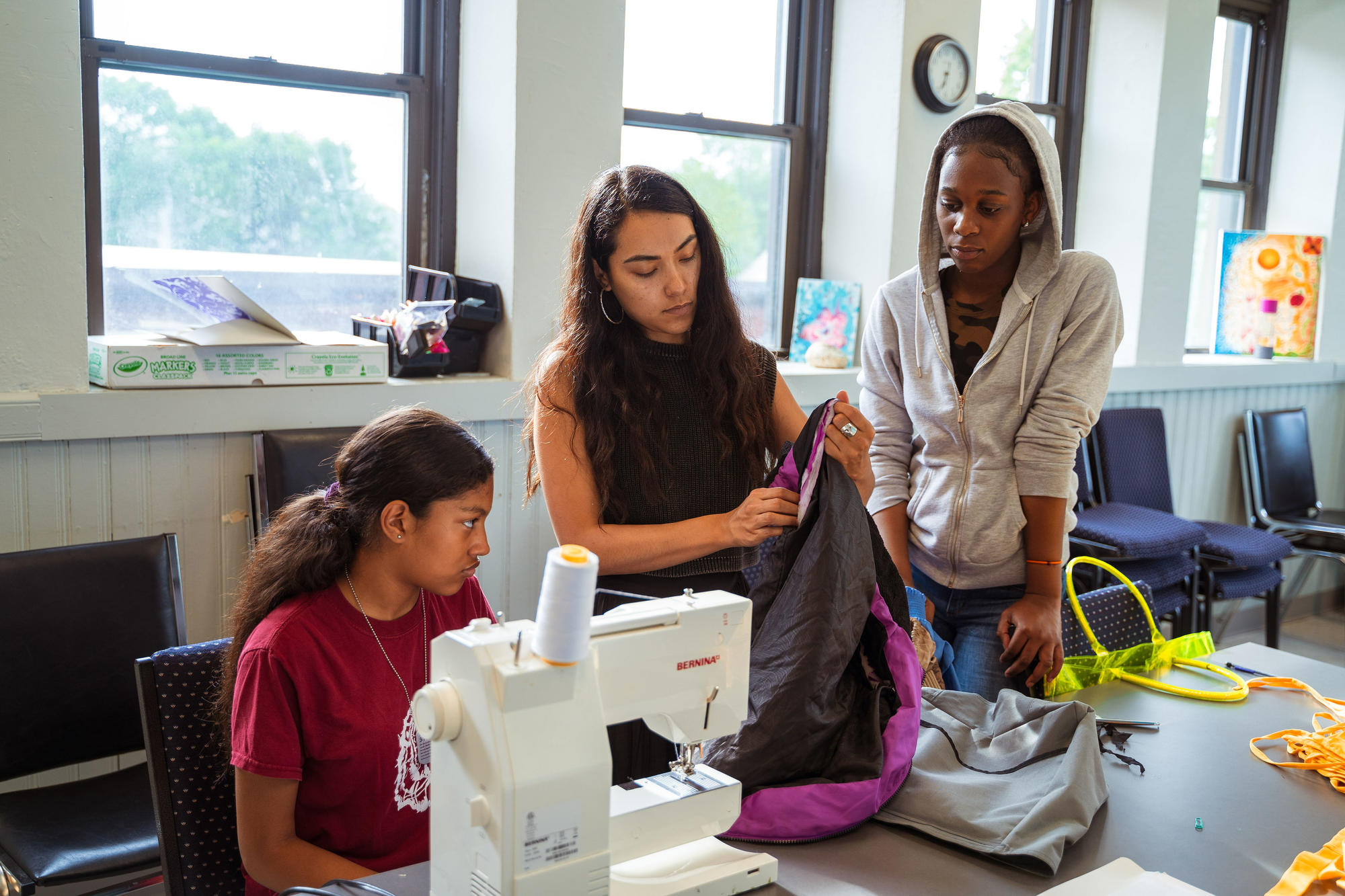 Nathalia JMag helps two Hyde Square Task Force Students with their sewing project.