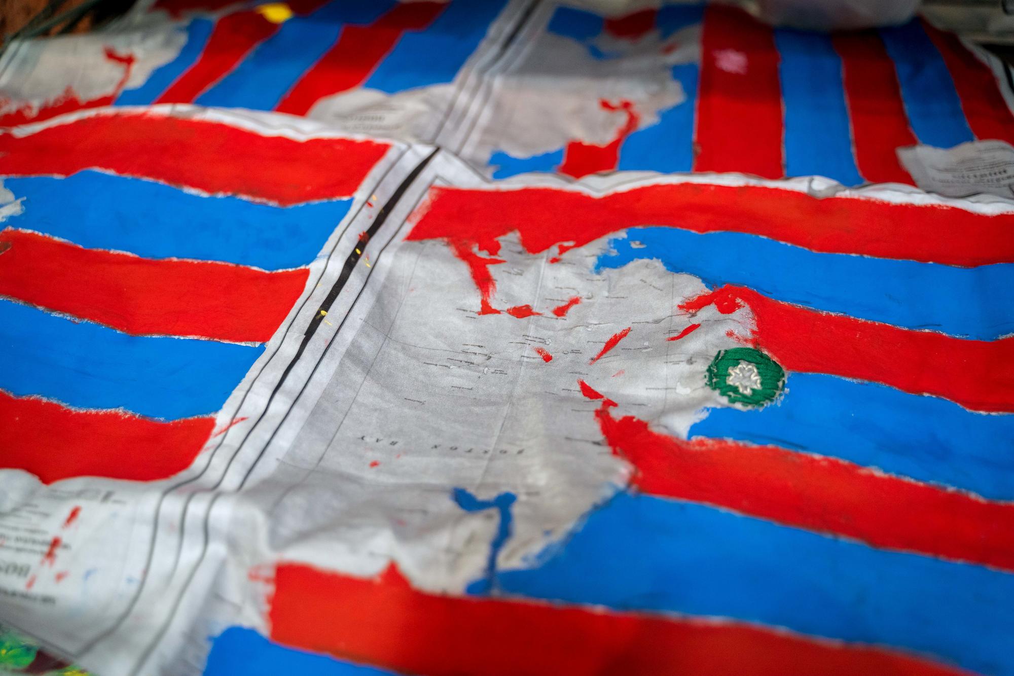 A close-up shot of a map-inspired textile with red and blue stripes obscuring the map beneath it, created by Urbano Project students. 