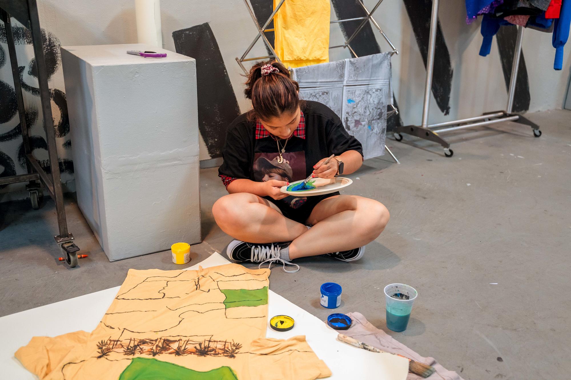 An Urbano Project student fills in hand-drawn sections of her garment with paint.